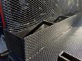 Close-up of a textured flatbed with a mesh safety fence and storage compartments on a Hino 358 truck