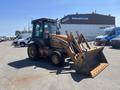 A 2011 Case 570 MXT backhoe loader with a front bucket and rear digging arm parked in a lot with vehicles in the background