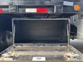 A 2009 Ford F-450 Super Duty with an open storage compartment displaying a black interior and metal hinges