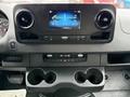 Dashboard of a 2023 Mercedes-Benz Sprinter featuring a central touchscreen display two air vents and a storage compartment with cup holders