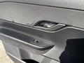 A close-up view of the interior door handle of a 2023 Fisker Ocean with textured black material and a button for unlocking the door