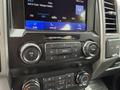 A 2019 Ford F-150 dashboard with a large touchscreen display showing radio information and various control knobs for volume and climate settings