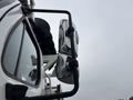 Close-up of a side mirror reflecting the view from a 2013 Freightliner 114SD truck showcasing its sleek design and chrome details