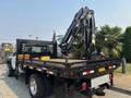A 2009 Ford F-450 Super Duty truck with a flatbed and a mounted crane on the rear side of the bed