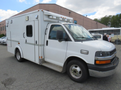 A white 2011 Chevrolet Express with markings and emergency lights on the roof designed for medical or service use