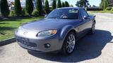 A silver 2007 Mazda Miata with a sleek design and distinct front grille is parked with its top down