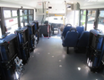 Interior view of a 2020 Chevrolet Express bus showing rows of blue seats and foldable seats along the aisle