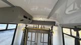 Interior view of a 2021 Ford Transit showing overhead storage compartments and a metal safety barrier in the passenger area