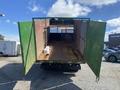 A 1997 Freightliner FL70 truck with open rear doors revealing an empty cargo space featuring a wooden floor and metal mesh fencing
