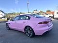 A pink 2020 Jaguar XE parked on a gravel surface showcasing its sleek design and sporty rims