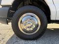 Close-up of a chrome wheel rim with multiple bolts and a rugged tire on a 2012 Ford Econoline E-450