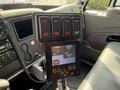A control panel with buttons labeled for liquid functions and a screen displaying settings for spread rate and width within a truck's interior