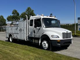 A 2004 Freightliner M2 truck with a silver body and a utility-style service bed featuring multiple compartments and an exhaust stack on the side