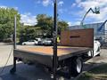 A 2014 RAM 5500 flatbed truck with a wooden bed and adjustable side rails visible in the foreground