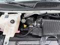 Engine compartment of a 2004 Chevrolet Express showing various components including the coolant reservoir and air intake assembly