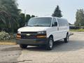 A white 2021 Chevrolet Express van with a black grille and chrome accents parked on a driveway