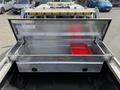 An open silver tool box with diamond plate texture mounted in the bed of a truck featuring red storage organizers inside