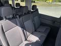 Interior view of a 2025 Ford Transit T-350 showing rows of gray upholstered seats with seatbelts and headrests