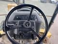 The steering wheel and controls of a 2012 John Deere 310SJ tractor with a black and silver design