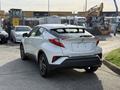 A white 2021 Toyota C-HR viewed from the rear left angle showcasing its sleek design and distinctive taillights
