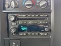 The dashboard of a 2004 Chevrolet Express showing the radio and climate control dials with digital display and multiple buttons