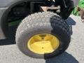 A close-up view of a tire mounted on a 2016 John Deere 1585 Terrain Cut featuring a yellow rim and heavily treaded black tire surface