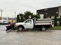 A white 2012 Dodge Ram 5500 with a snow plow attached in the front and a large metal box in the back