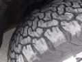 A close-up of a tire with a rugged tread pattern on a 2015 Chevrolet Silverado 1500