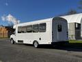 A white 2014 Ford Econoline shuttle bus with large windows and a sliding door at the rear parked on a street