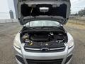 A 2014 Ford Escape with its hood raised revealing the engine compartment and various components inside