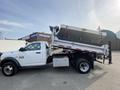 A 2016 RAM 5500 dump truck with a raised dump bed raised and a white exterior with a silver trim and chrome wheels