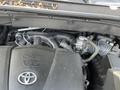 A close-up view of the engine bay of a 2018 Toyota Highlander showing the V6 engine components and the Toyota logo on the engine cover