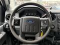 Steering wheel of a 2015 Ford F-350 SD with control buttons and a Ford logo prominently displayed in the center