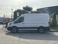 A white 2016 Ford Transit 150 van parked on a concrete surface with a side view showing its elongated body and simple design