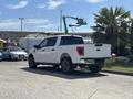 A 2021 Ford F-150 pickup truck in white with a crew cab and black wheels parked on a paved surface