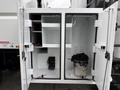 Open doors of a storage compartment on a 2021 Freightliner M2 106 showing shelves and hooks with a bucket and chain on the floor