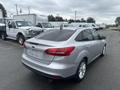 A 2018 Ford Focus in silver with a sleek rear design parked in a lot with other vehicles behind it