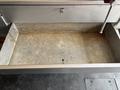 An empty metal storage compartment with a gray surface and a lever on the side of a 2011 Workhorse W62