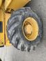 A close-up of the rear tire of a yellow 2012 John Deere 310SJ construction vehicle showing deep treads and a sturdy wheel hub