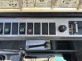 Control panel of a 2010 Bobcat E80 with various switches and buttons including a key ignition and a wrench placed on the floor