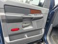 A door panel of a 2006 Dodge Ram 2500 featuring a gray fabric finish wood accents and control buttons for windows and locks