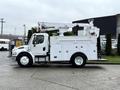 A 2005 Freightliner M2 106 bucket truck with a white exterior and a raised hydraulic lift arm on the roof, featuring storage compartments on the sides