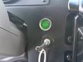 Close-up of a green engine start button and an ignition key in a 2017 Freightliner MT45 dashboard