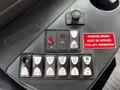 Control panel of a 2015 Chevrolet Express featuring buttons for door operation, lights, and lift functions along with a warning label about the parking brake for lift operation