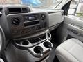 Interior view of a 2024 Ford E-450 showing the dashboard radio controls and cup holders with gray upholstery