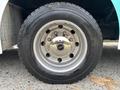 Close-up of a silver wheel rim with a shiny hubcap mounted on a large black tire featuring bold tread patterns