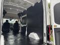 A 2020 Ford Transit 250 van interior showcasing a large cargo space with black flooring and seats visible at the front
