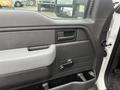 Interior door panel of a 2013 Ford F-150 featuring a black and gray design with a handle and control knob for the window