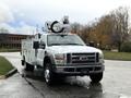 A white 2008 Ford F-550 utility truck with a bucket lift mounted on top and utility compartments on the sides parked in a lot