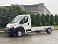 A white 2023 RAM Promaster 3500 chassis cab with no cargo bed is parked with its front view facing the camera and a flatbed frame visible in the rear